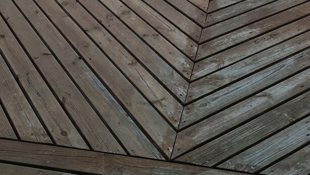 A wooden deck with a view of a green landscape and distant horizon. - Guesthouse Stekkatún (Höfn)