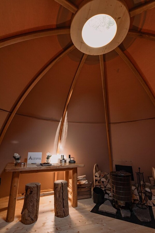 A cozy interior with a wooden table, stools, a heater, and a sign reading 'ALTIPIK'. - Altipik (Mont-Saxonnex)