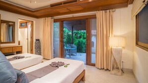 Une chambre d’hôtel avec un lit double, une table de chevet, une lampe, une chaise et une vue sur le jardin, visible à travers la porte-fenêtre coulissante.
