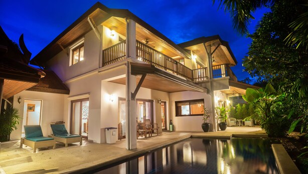 Une maison à deux étages dotée d’un balcon, d’une piscine et de mobilier d’extérieur.