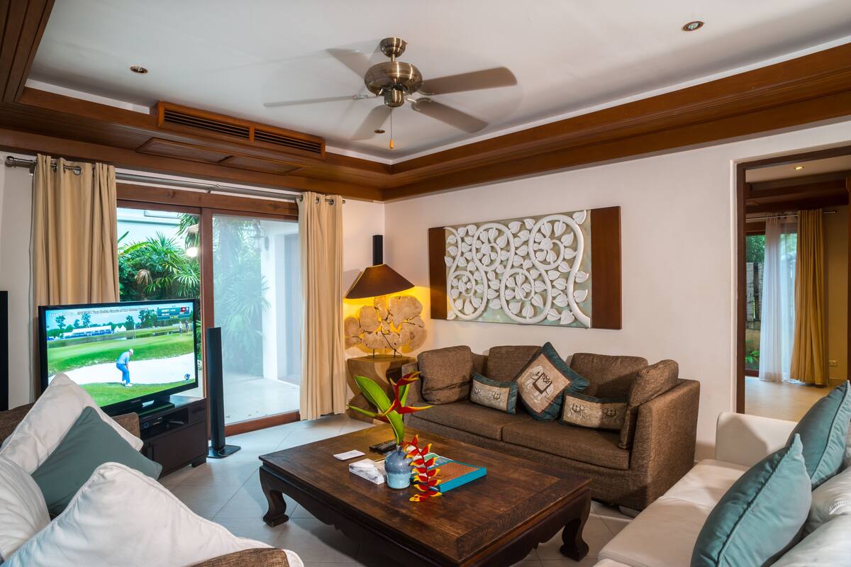 A living room with a television, sofa, coffee table, and decorative items.