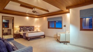 Une chambre à coucher comprenant un lit, des tables de chevet, une commode, une lampe sur pied, un canapé et une fenêtre avec des stores.