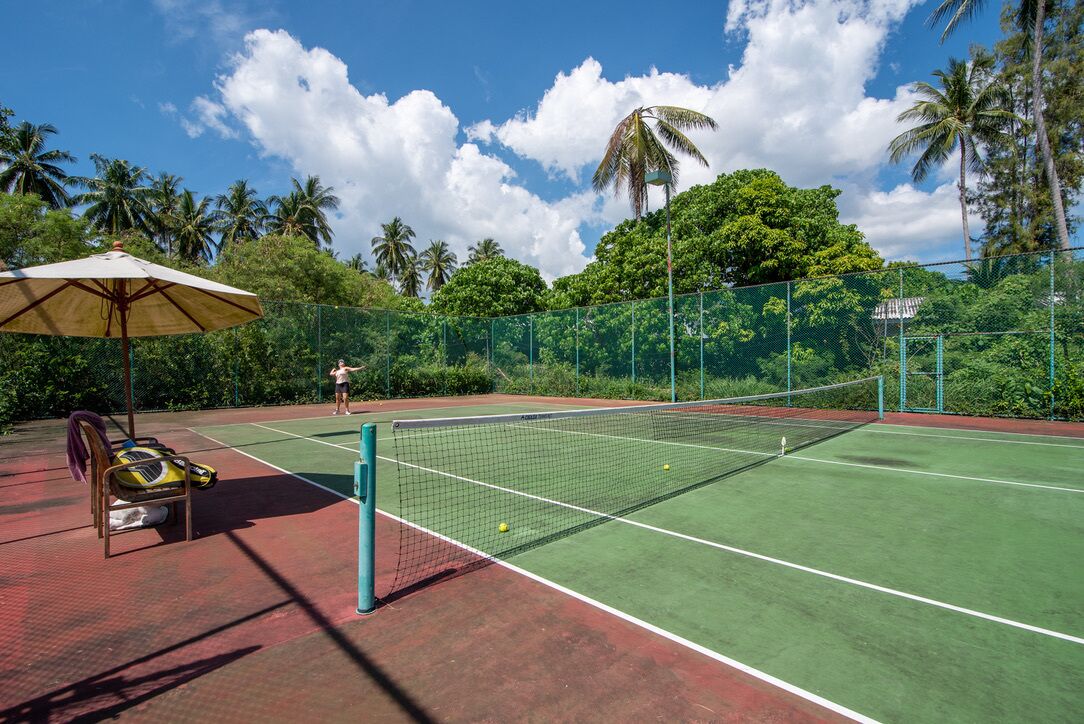 Un court de tennis extérieur avec un filet, une chaise et une balle de tennis.