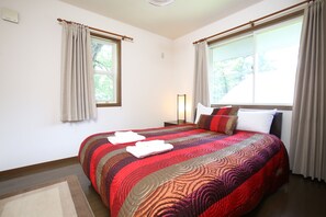 A bedroom with a large bed, two windows with curtains, a bedside table, and a nightstand. - Sumi Villa Hakuba (Hakuba)