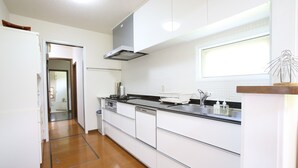 A modern kitchen with white cabinets, a stainless steel sink, and a wooden floor. - Sumi Villa Hakuba (Hakuba)