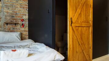Une chambre avec un lit en bois, un mur en briques, une porte coulissante de style grange et un tapis en peau de vache.