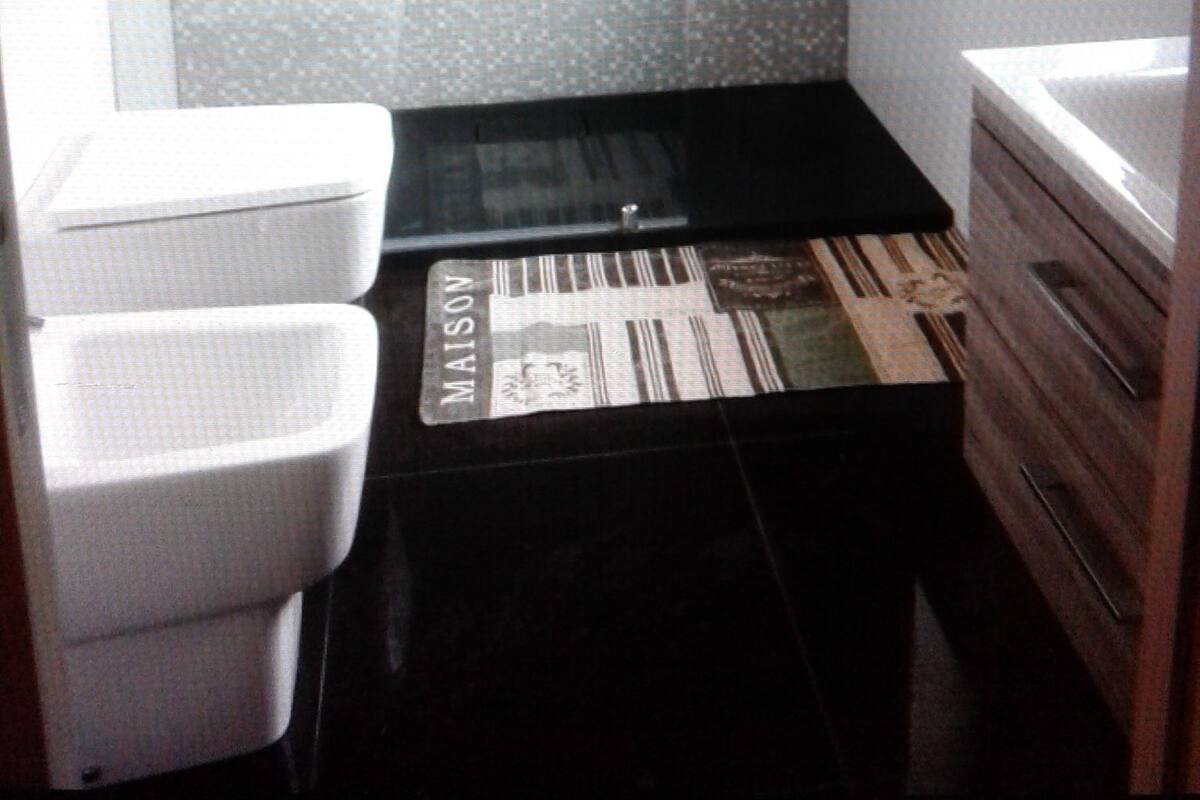 Un baño pequeño con ducha, lavamanos y retrete.