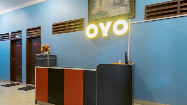A reception desk with a 'OYO' sign, a flower vase, and a painting on the wall. - Hotel O Titipapan Residence (Medan)