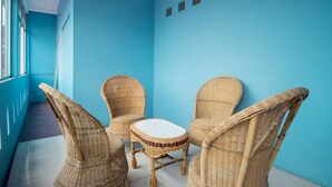 A room with blue walls, wicker furniture, and a small table. - Hotel O Titipapan Residence (Medan)