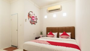 A bedroom with a bed, a nightstand, a wall decoration, and an air conditioning unit. - Hotel O Titipapan Residence (Medan)