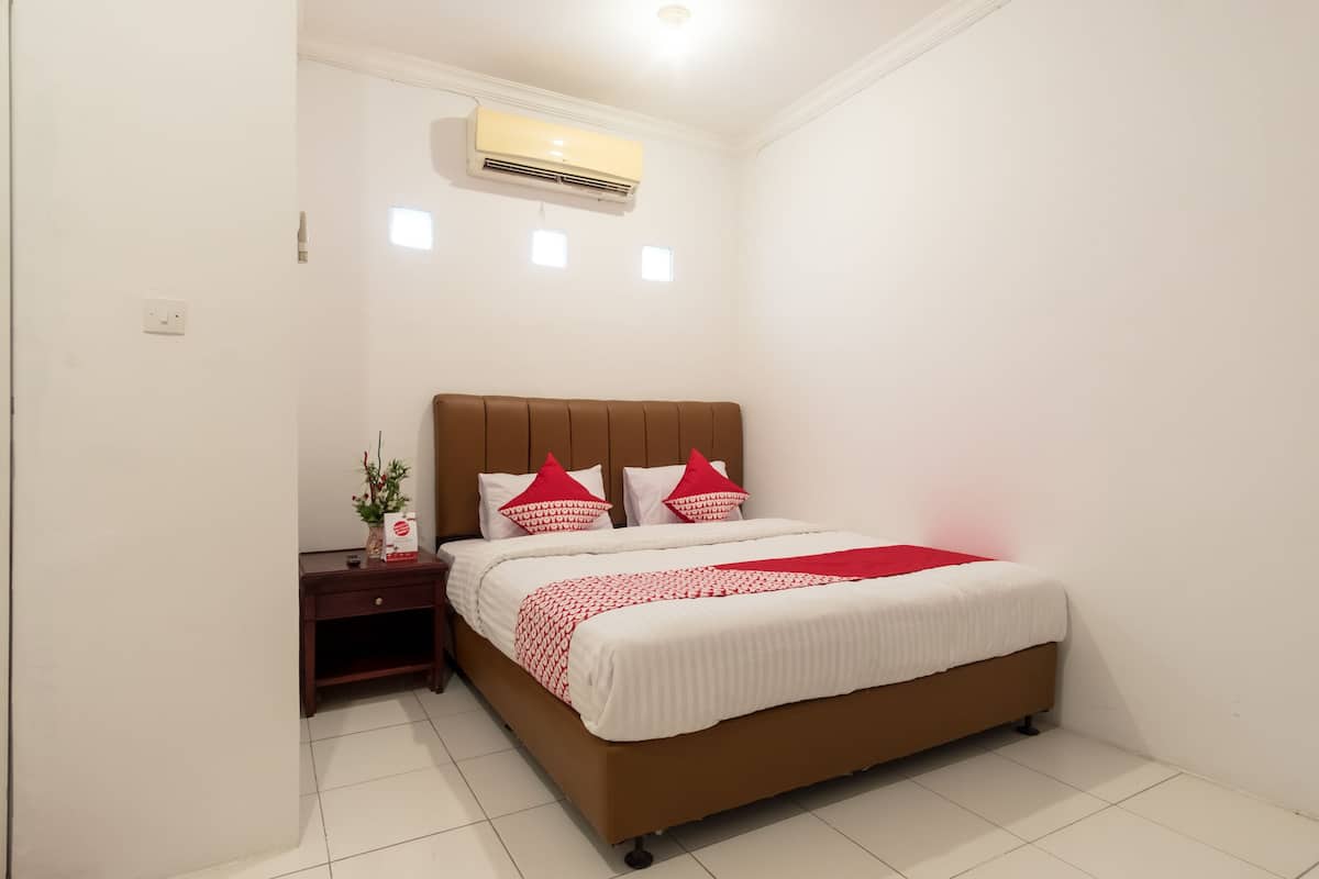 A bedroom with a bed, nightstand, and wall-mounted air conditioner.