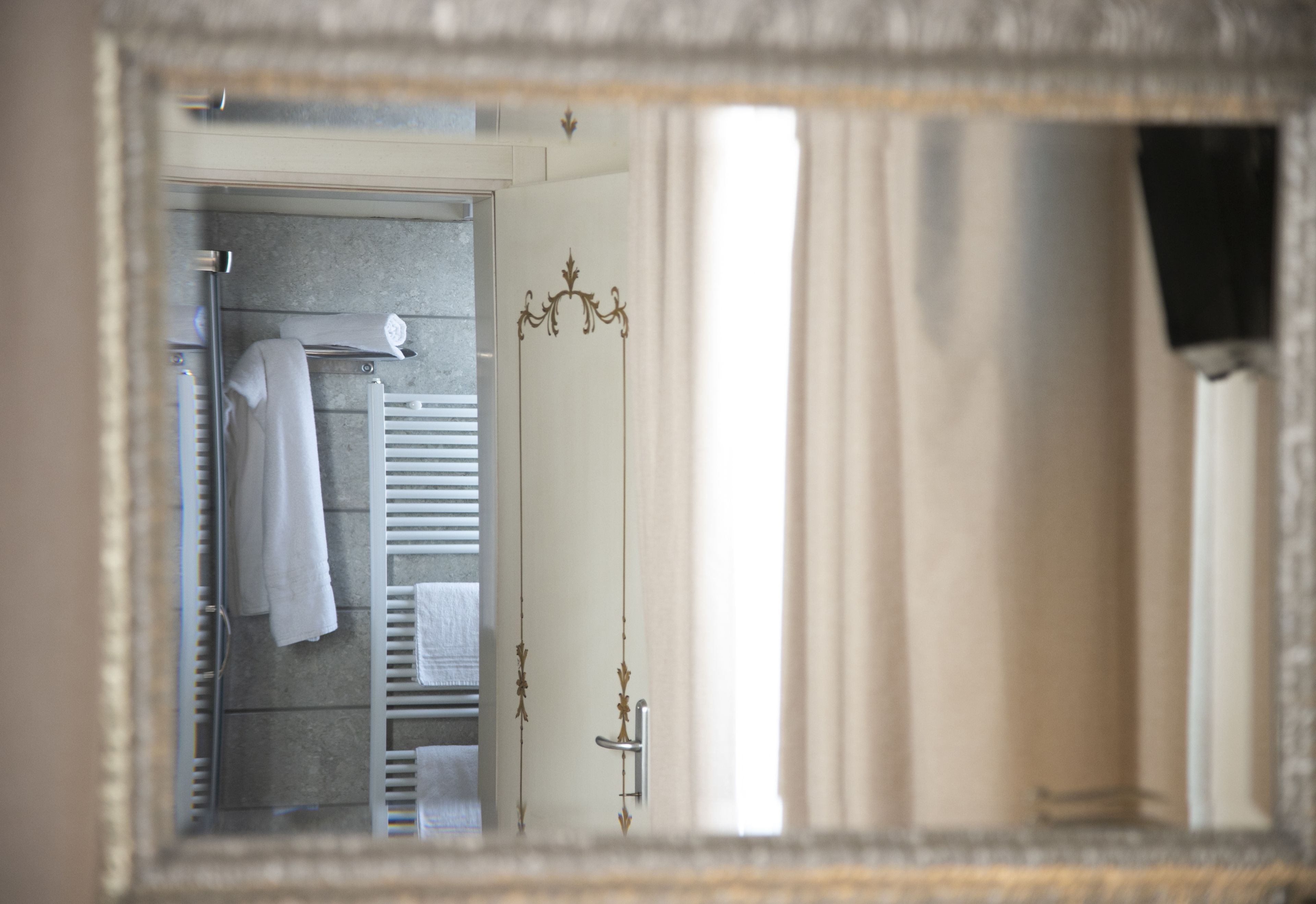 Une salle de bain avec un miroir qui reflète un porte-serviettes et une zone de douche.