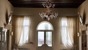 Un'ampia stanza con un'imponente porta ad arco, un lampadario e una panca.