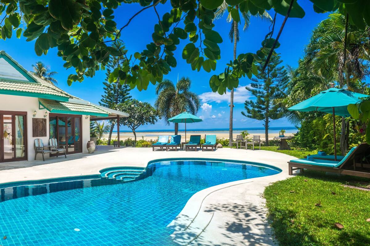 Un resort con piscina, sillas de descanso y vistas a la playa.