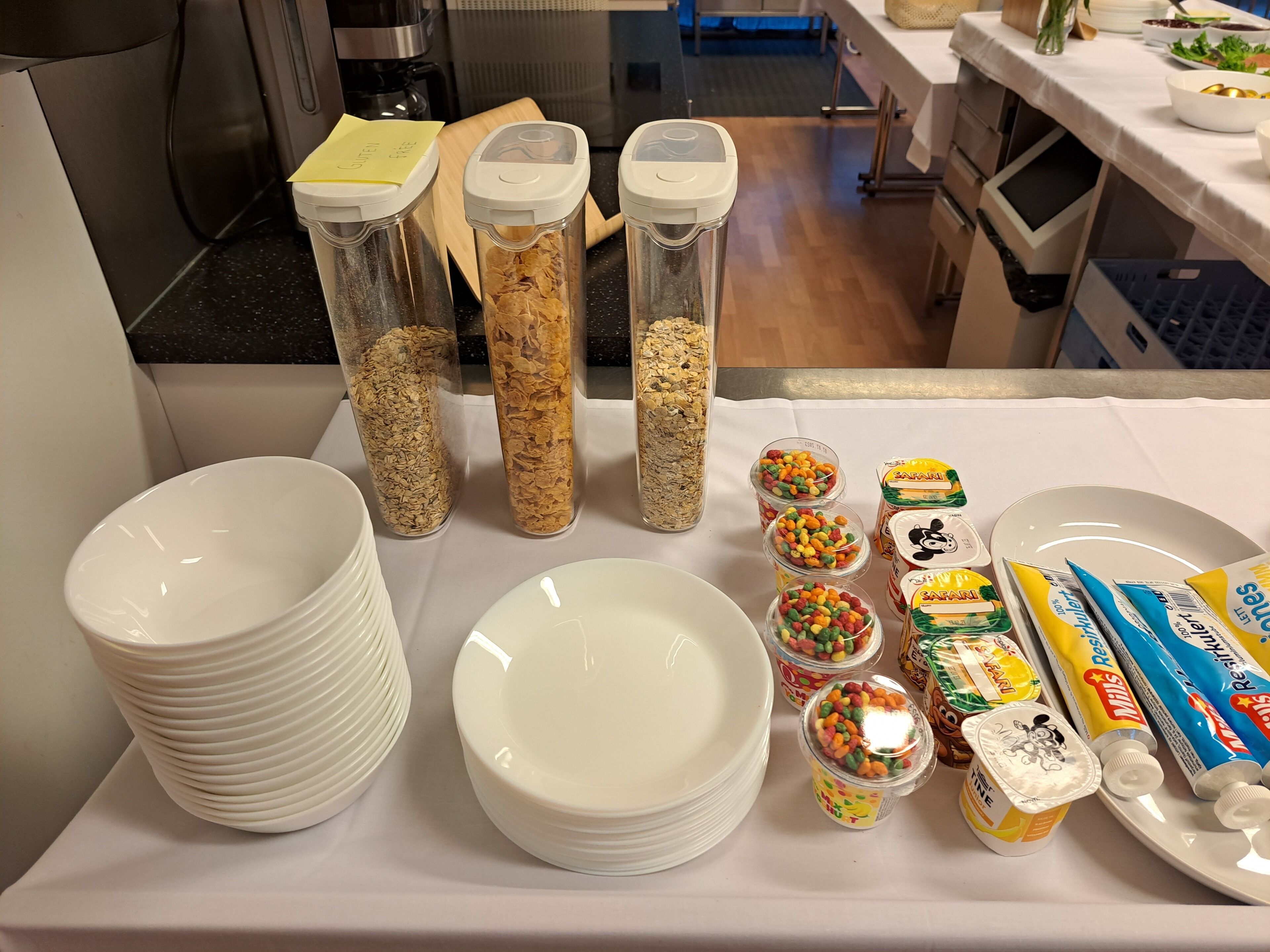 Una mesa con diversos alimentos y recipientes, como cereales, bocadillos y salsas.