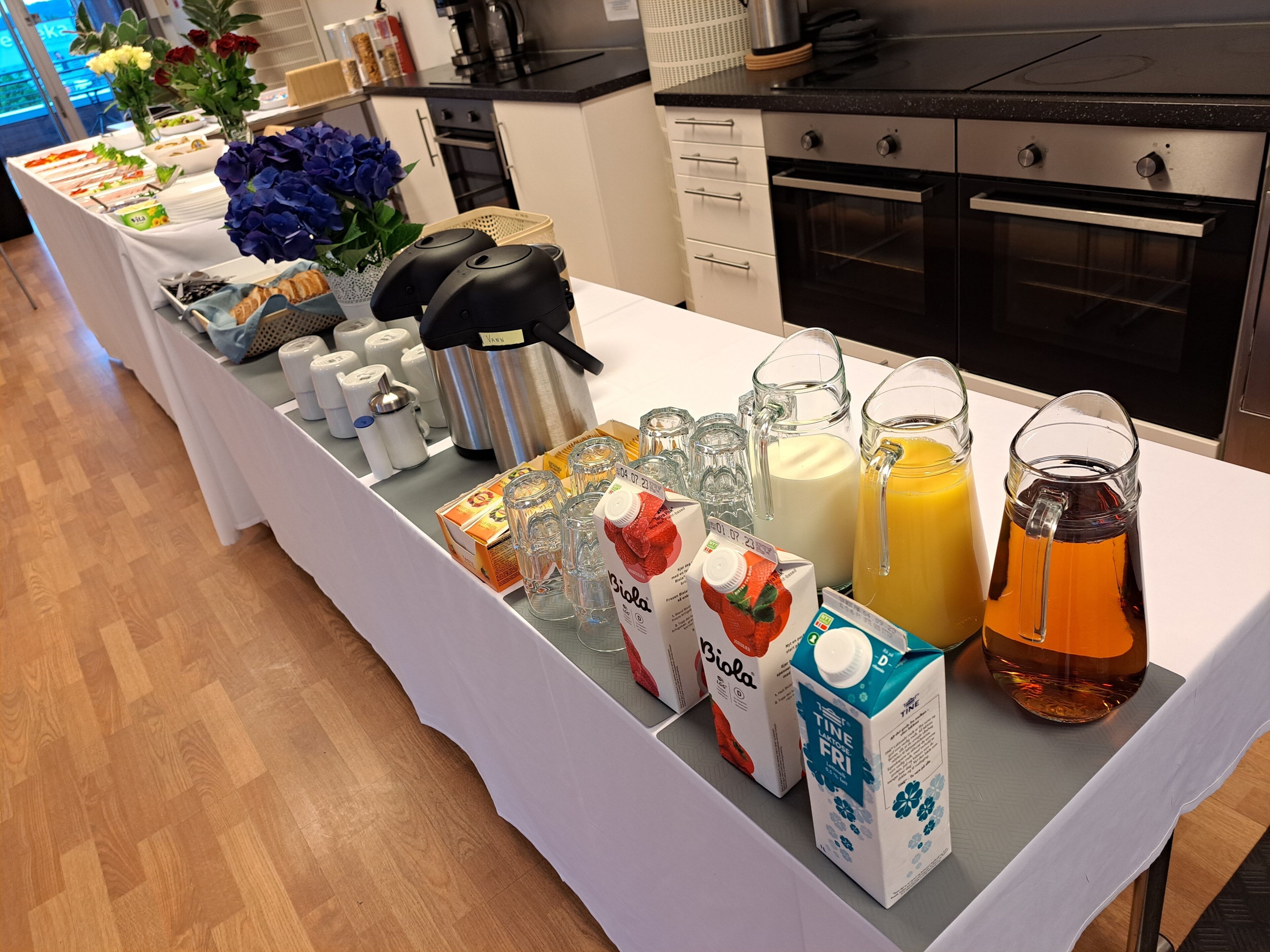 A breakfast buffet table with various food items, beverages, and a coffee maker.