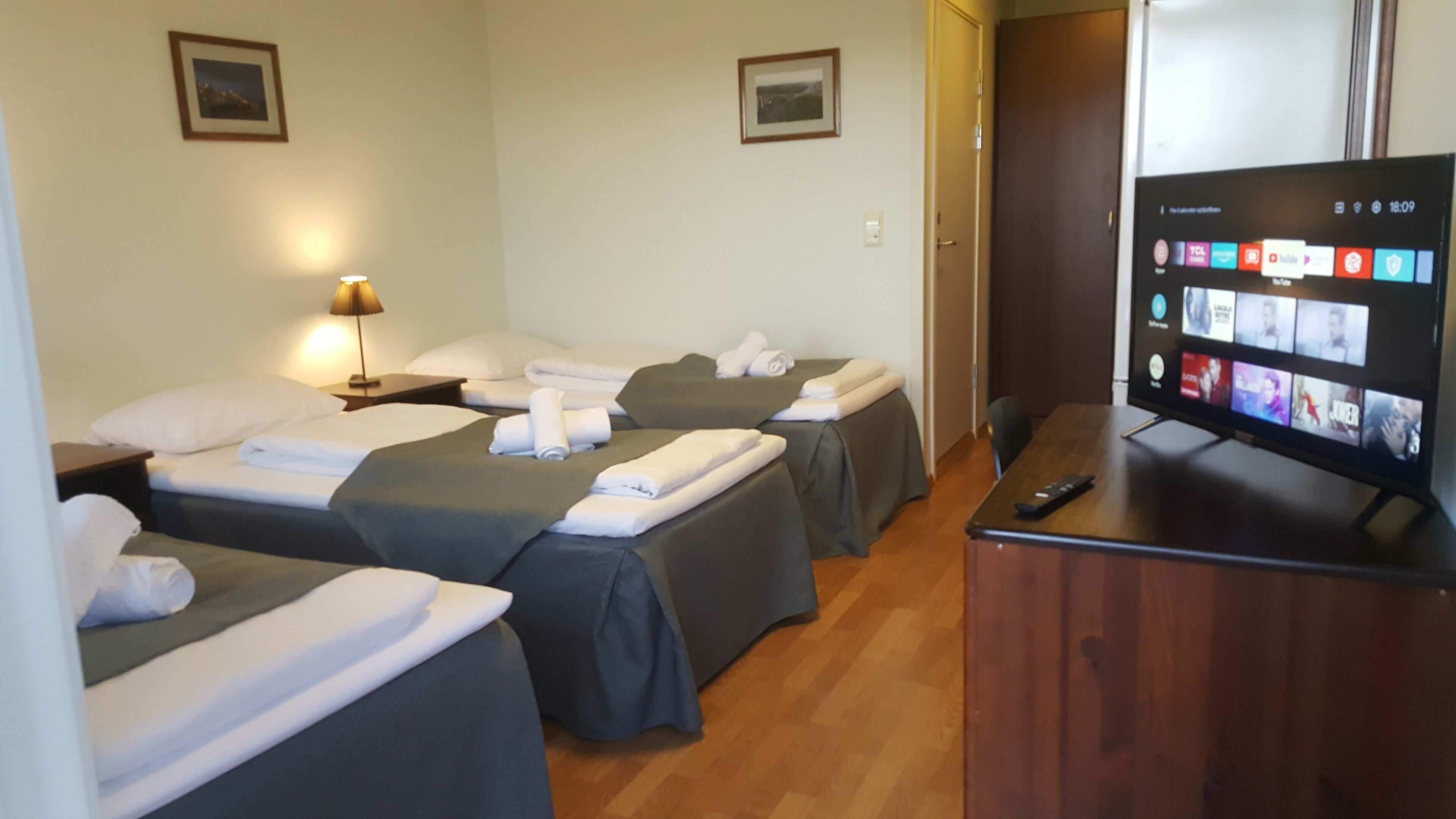 Habitación de hotel con dos camas, televisión y escritorio.