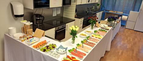 A buffet setup in a modern kitchen with white cabinets, stainless steel appliances, and a wooden floor.