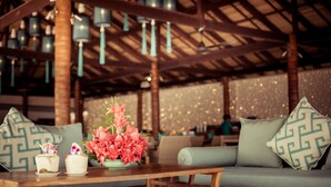 A cozy seating area with a wooden table, a floral centerpiece, and patterned cushions. - Baan Tawan (Koh Samui)