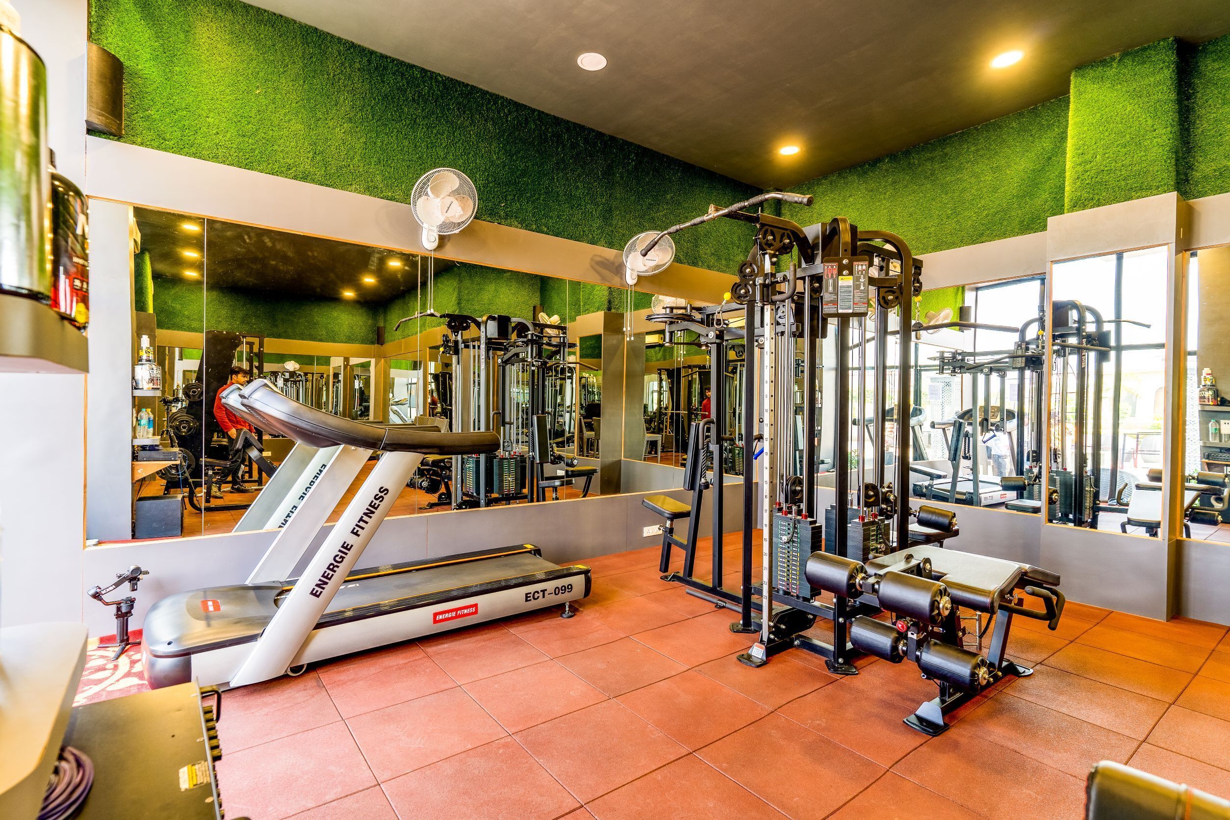 A gym with exercise equipment, a treadmill, and mirrors on the walls.