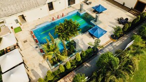 An aerial view of a hotel courtyard with a swimming pool, outdoor seating, and palm trees. - The Radiant Resort (Gorakhpur)