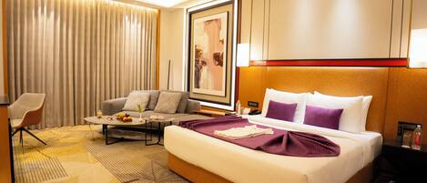 Une chambre d’hôtel avec un grand lit, un canapé, une table basse et un fauteuil.