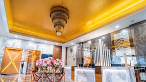 A hotel reception area with a marble floor, a chandelier, and a reception desk. - The Radiant Resort (Gorakhpur)