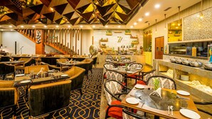A restaurant with a geometric ceiling design, multiple dining tables, and a variety of chairs. - The Radiant Resort (Gorakhpur)