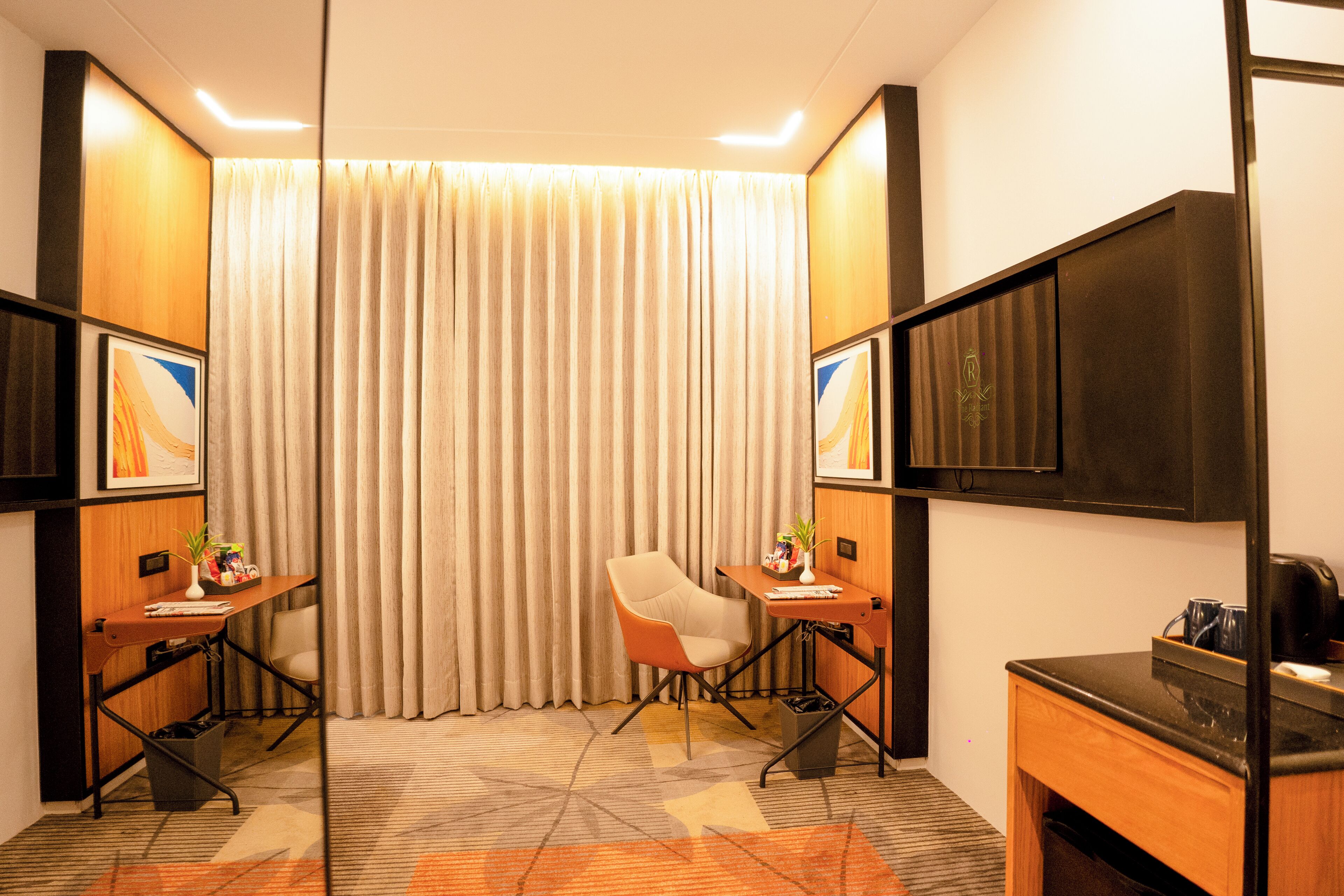 Une chambre d’hôtel équipée d’un bureau, d’une chaise, d’une télévision et de rideaux.