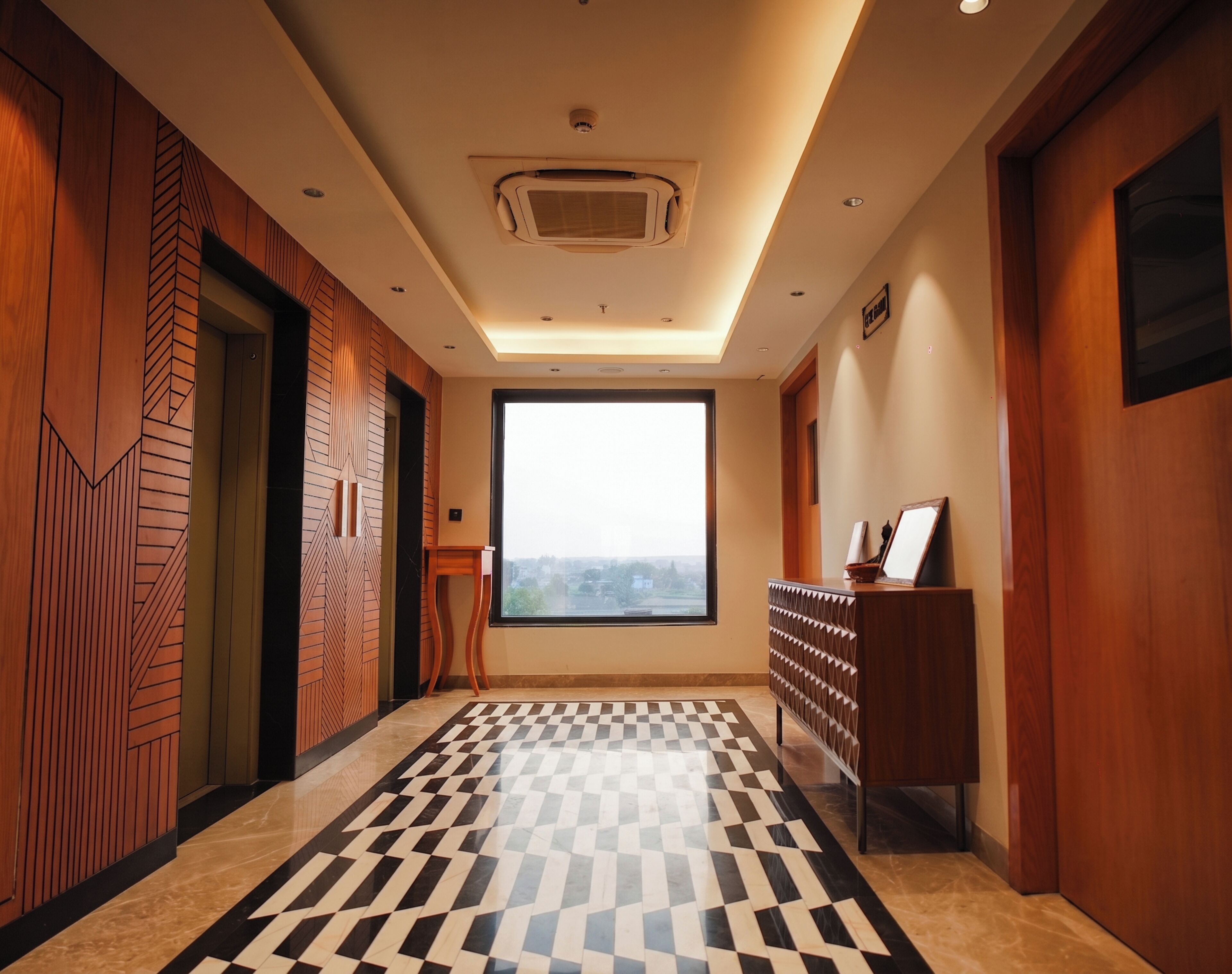 A hotel hallway with a checkered floor, wooden paneling, a large window, and a reception desk.