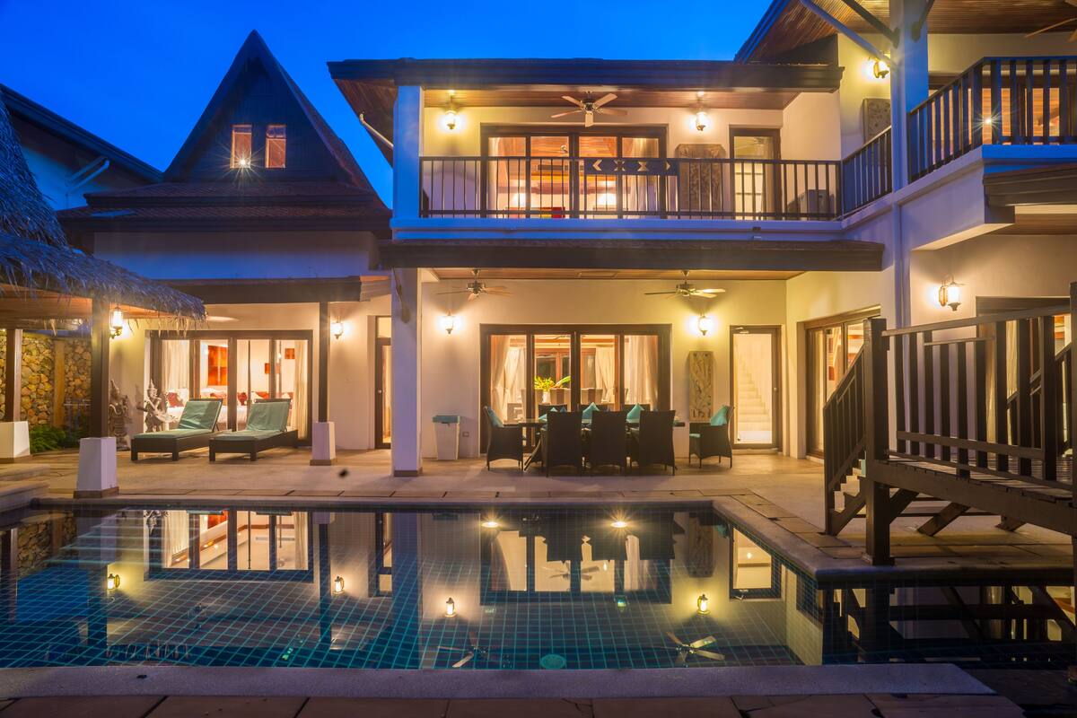 A two-story building with a swimming pool, outdoor seating, and a balcony.