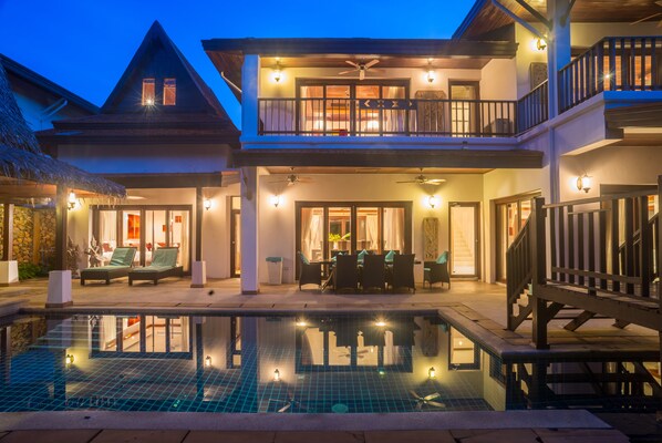 A two-story building with a swimming pool, outdoor seating, and a balcony.
