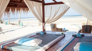 A beachside cabana with wooden flooring, two beds with patterned bedding, and a view of the beach. - Baan Chang (Koh Samui)