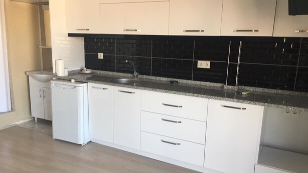 Una cocina moderna con armarios blancos, un salpicadero negro y una encimera de granito.