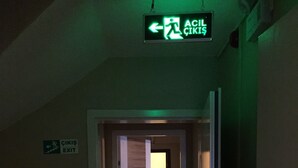 Un pasillo con una señal de salida y una puerta que da a una habitación.