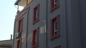 Un edificio de varios pisos con ventanas de marco rojo y unidades de aire acondicionado adheridas a las paredes exteriores.