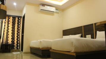 A hotel room with two beds, a ceiling-mounted air conditioner, and a patterned curtain.
