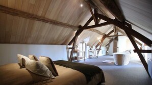 Une chambre mansardée chaleureuse, avec un lit, des oreillers et un grand panier en osier.