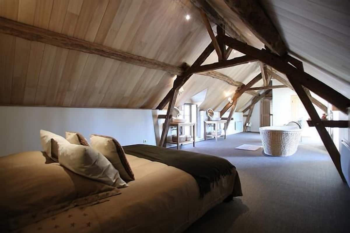 A cozy attic bedroom with a bed, pillows, and a large woven basket.