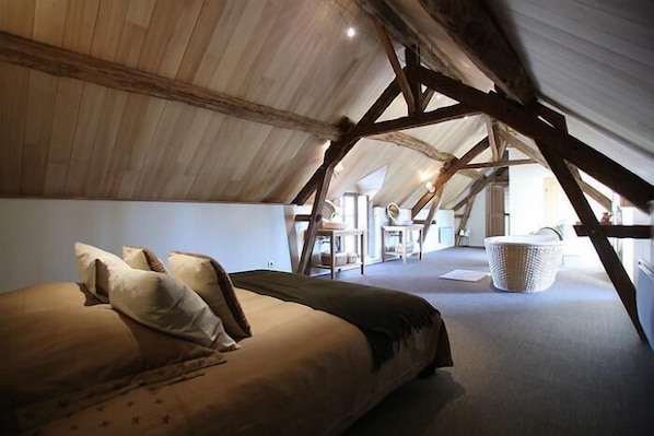 A cozy attic bedroom with a bed, pillows, and a large woven basket.