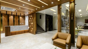 Eine moderne Hotelhalle mit einer Rezeption, Ledersitzmöbeln und einer Treppe zu den oberen Etagen.