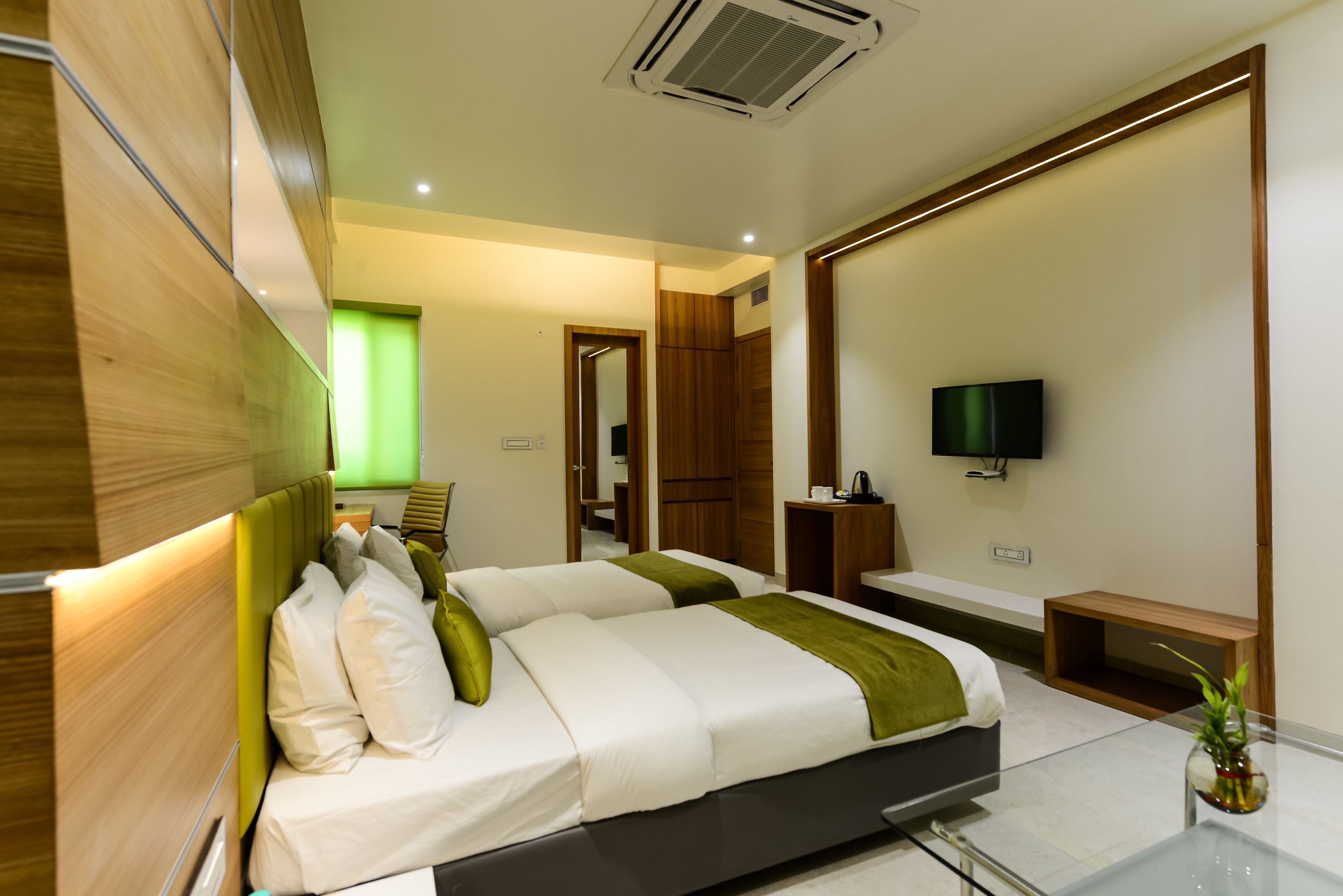A modern hotel room with a large bed, a TV, and a desk.