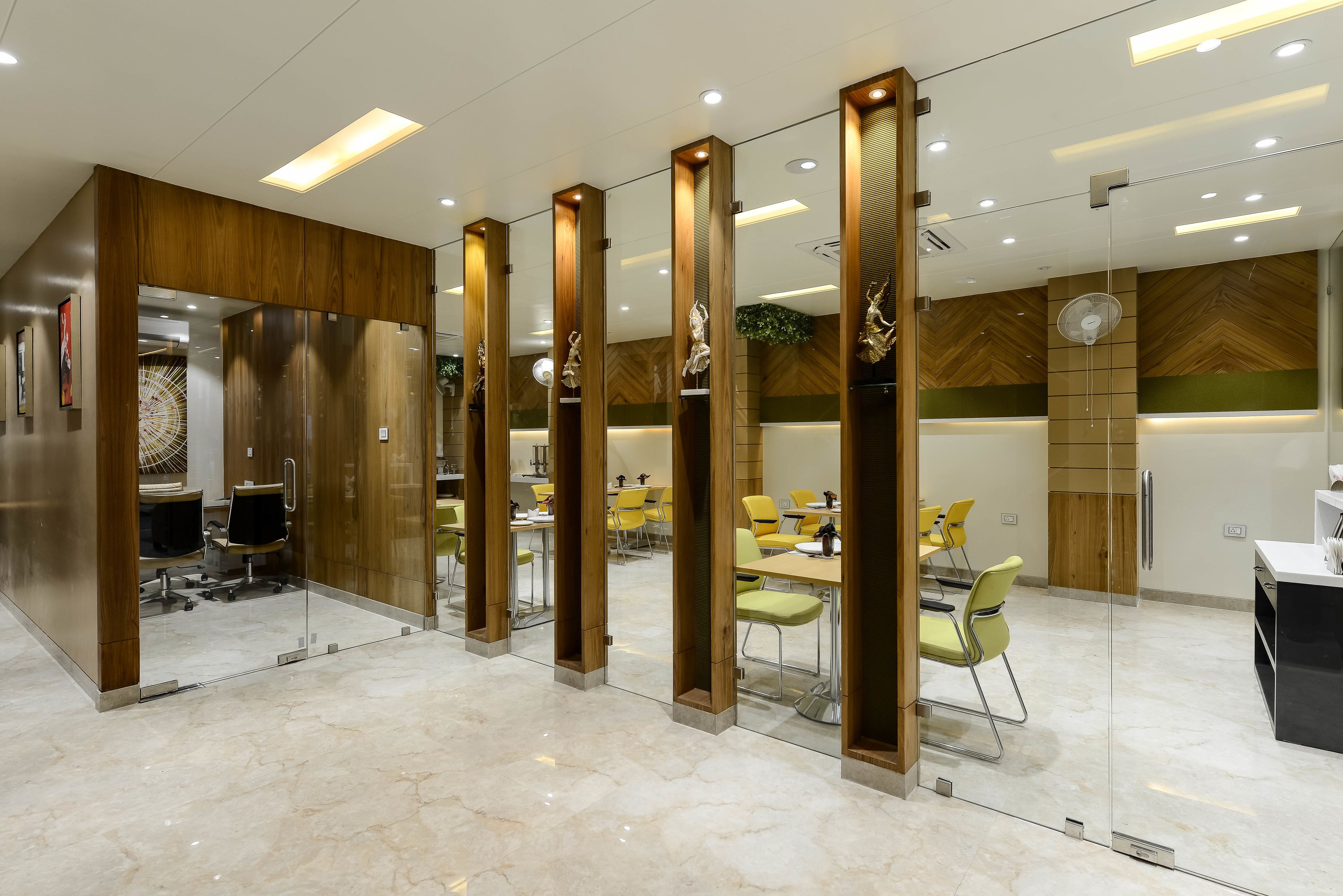 A modern office space with glass partitions, wooden accents, and a polished marble floor.