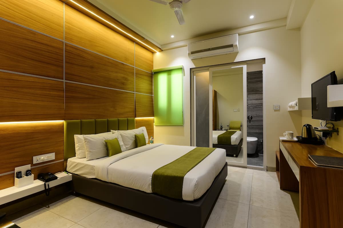 A modern hotel room with a large bed, bedside table, and a mirror.