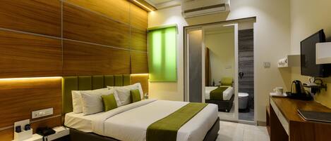 A modern hotel room with a large bed, bedside table, and a mirror.