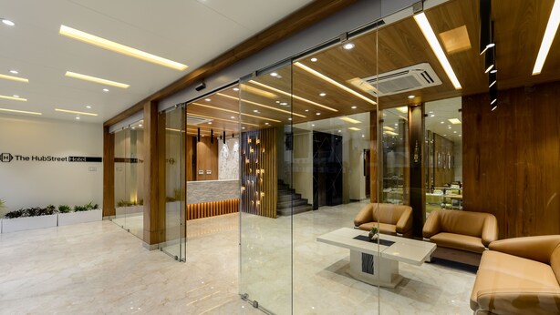 Eine moderne Hotellobby mit Glaswänden, einer Rezeption, Ledersitzmöbeln und einem Marmorboden.