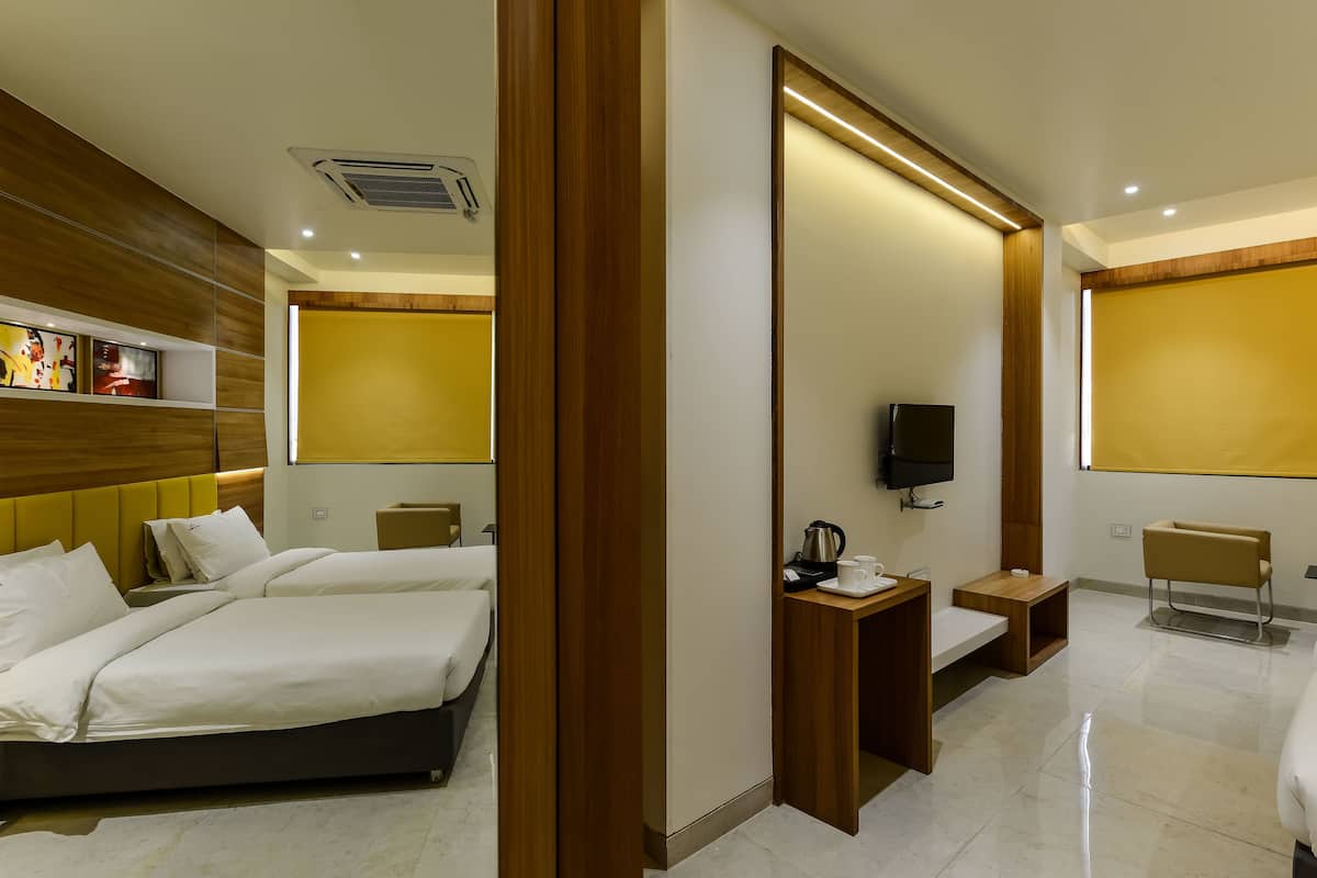 A hotel room with a bed, bedside tables, a TV, and a seating area.