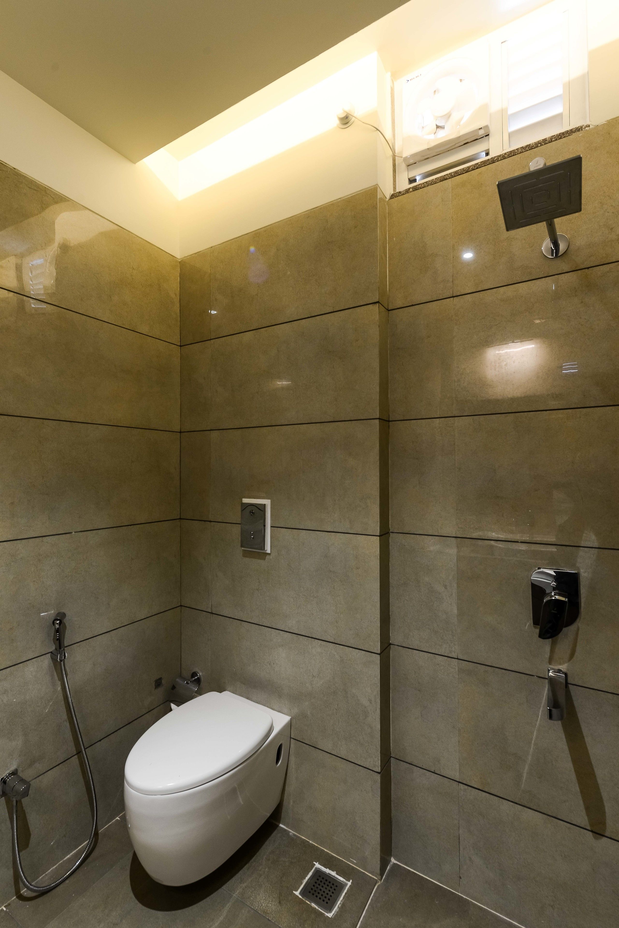 A modern bathroom with a toilet, shower, and a control panel on the wall.