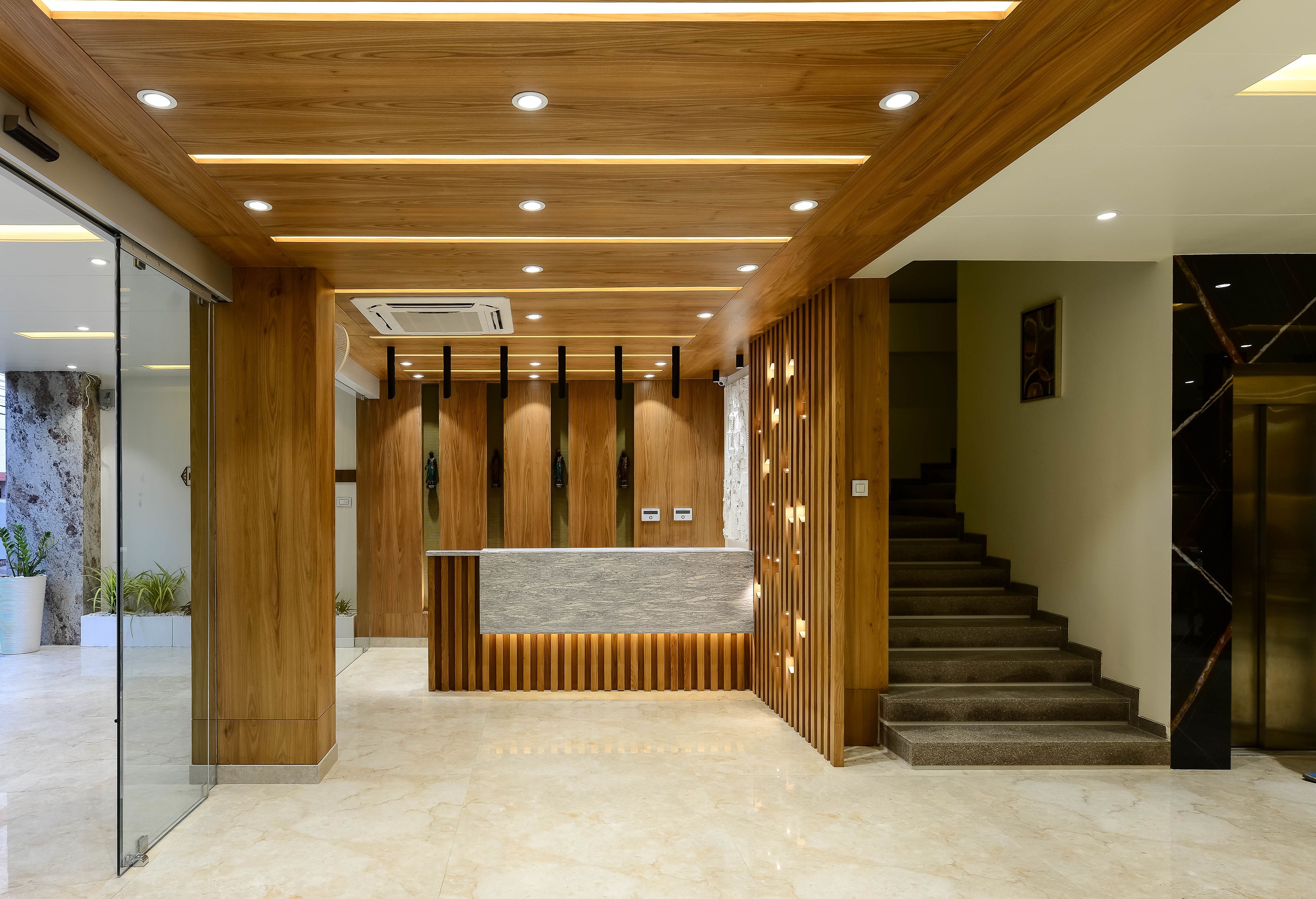 A reception area with a wooden reception desk, a staircase, and a glass wall on the left.