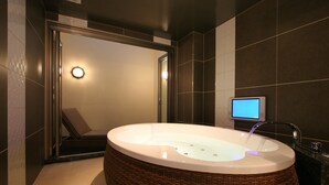 A modern bathroom with a large freestanding bathtub, a digital screen, and a mirror. - HOTEL W - Adults Only (Koshigaya)